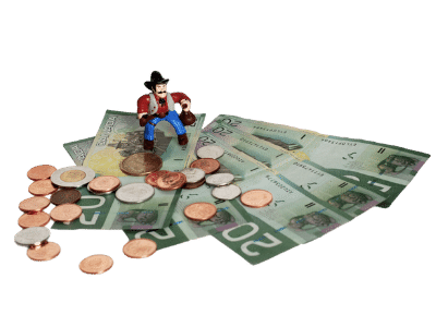 A toy cowboy holding bags of money standing over a spread of Canadian $20 bills with some pennies, quarters, dimes, and toonies scattered over top of them.