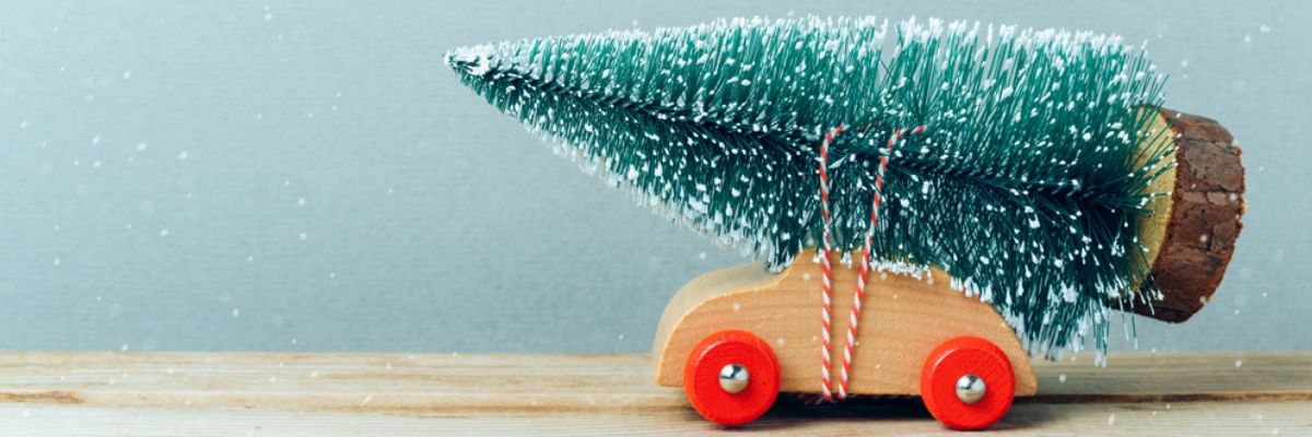 Wooden toy car carrying a miniature Christmas tree symbolizing December as the best to by a car in Ontario.