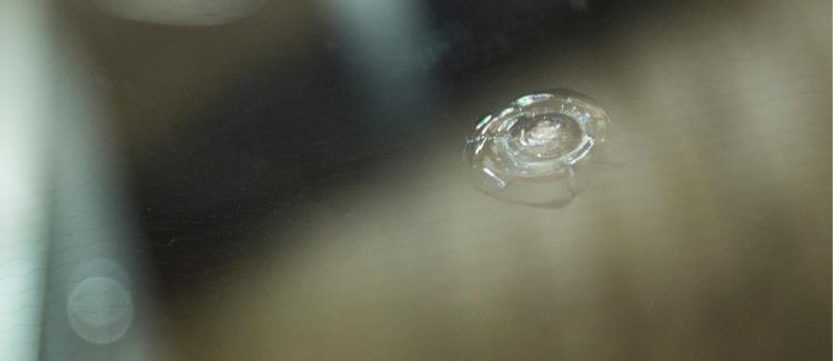 A small circular chip in a car's windshield, about the size of a quarter.