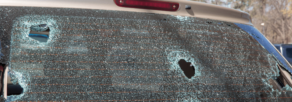 Large holes in an SUV's back windshield from hail pellets.