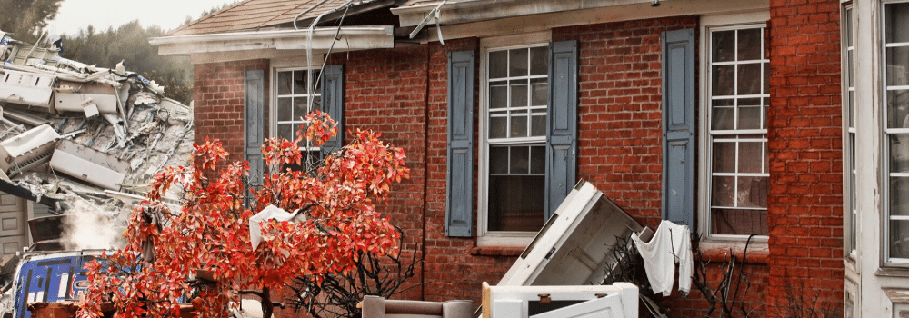 A redbrick house damaged by a tornado and debris.