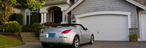 Convertible sitting in the parking lot of a house with a double car garage.