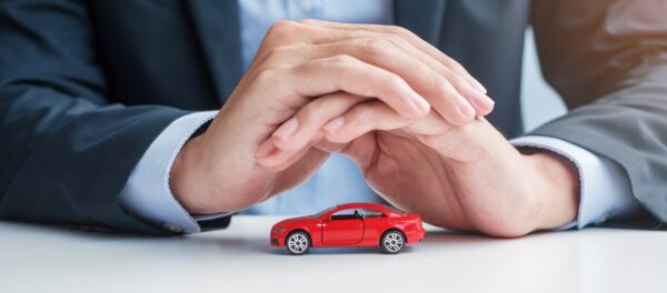 A persons hands covering a toy car demonstrating insurance coverage as they explain third party liability