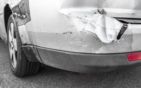 a car sits damaged by an accident while its owner finds out about how to pay deductiblels